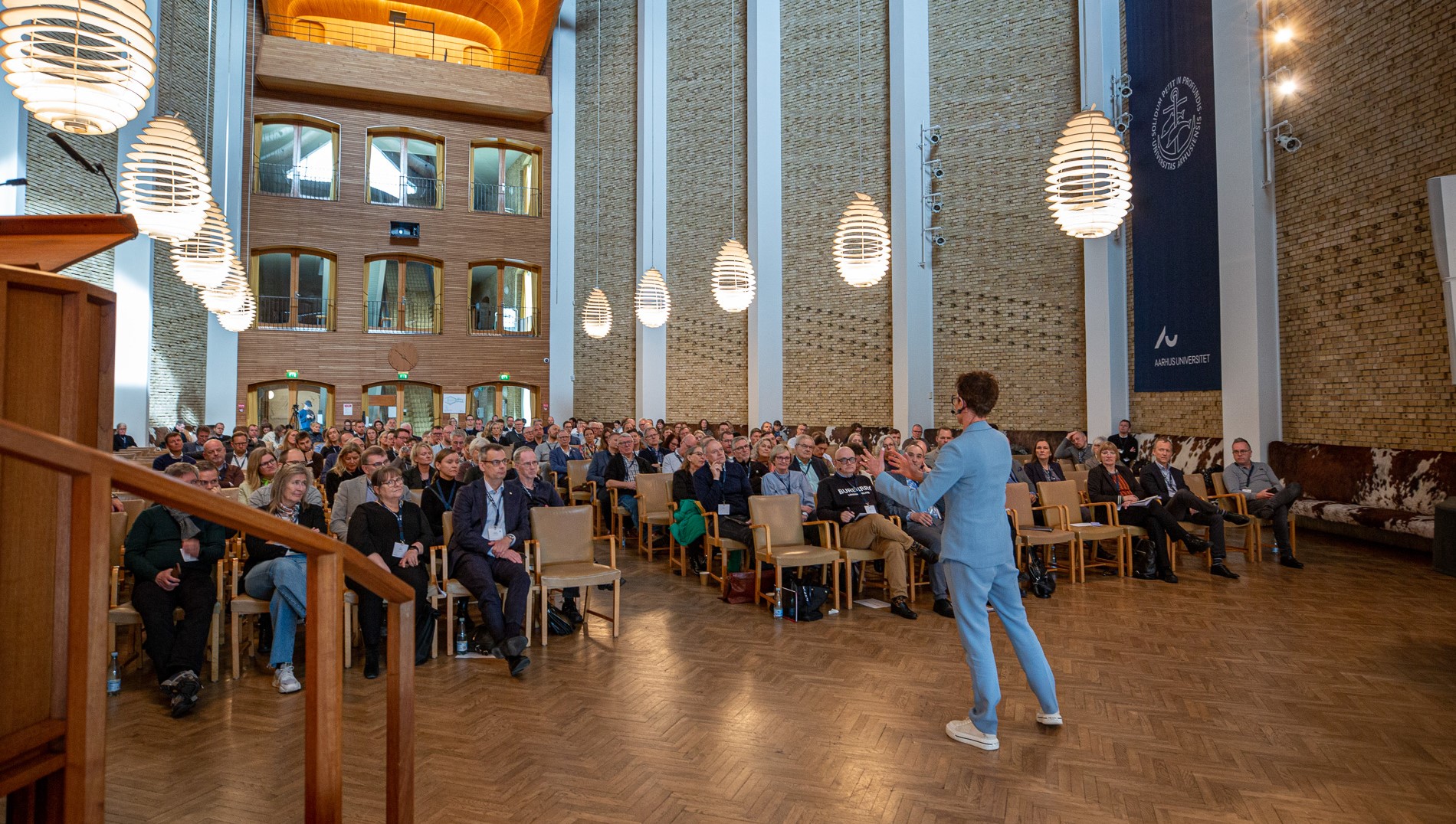 Marianne Kirkegaard præsenterer foran publikum til Happy Hours på Aarhus Universitet